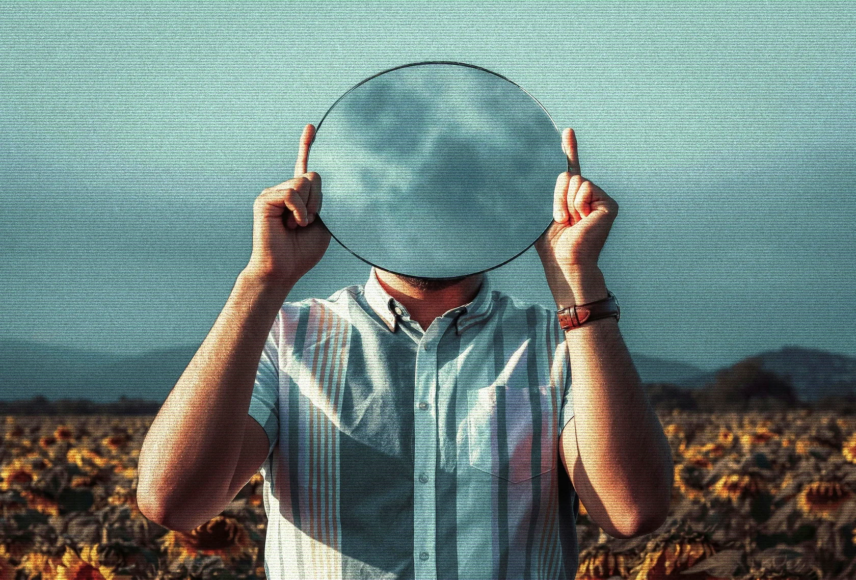 Man holding a circular mirror in front of his face